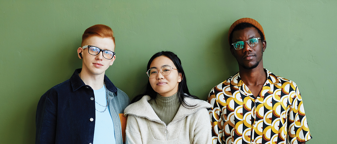 Minimal portrait of diverse creative team looking at camera while standing against green wall in office