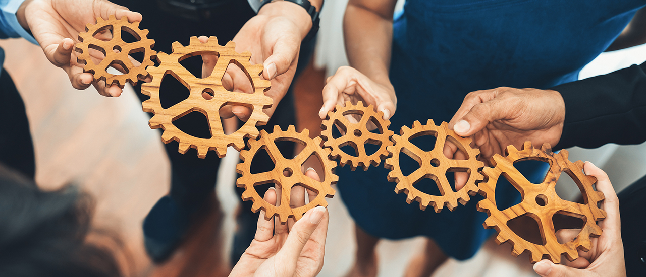 Office worker holding cog wheel as unity and teamwork in corporate workplace concept. Diverse colleague business people showing symbol of visionary system and mechanism for business success. Concord
